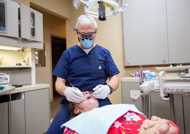 Dr. Ukena works on a patient's mouth as part of a tooth extraction dental visit.